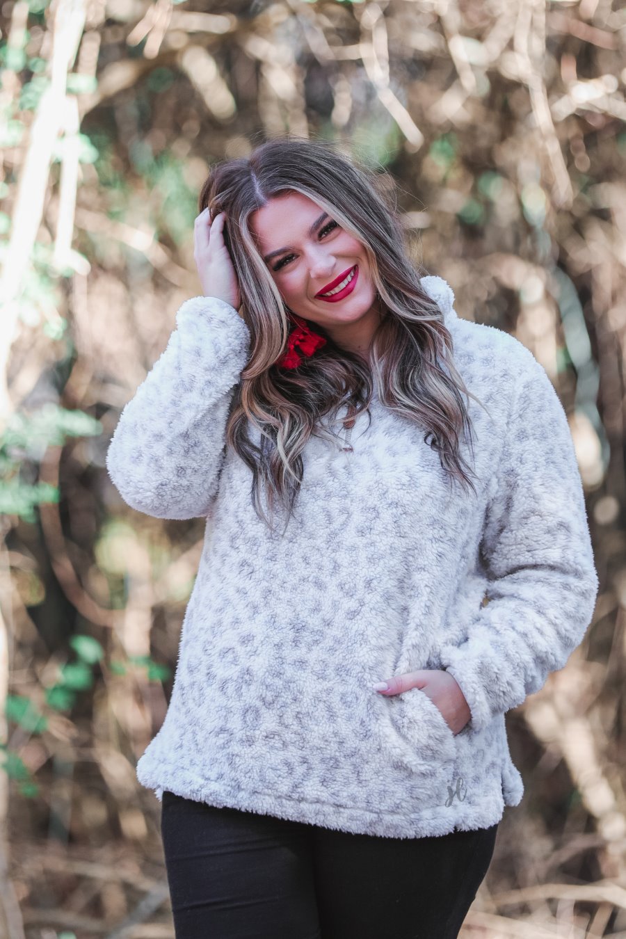 a long-sleeve fluffy pullover with a quarter zip, convenient front pockets, and a foldable collar on a neutral leopard print sherpa fabric