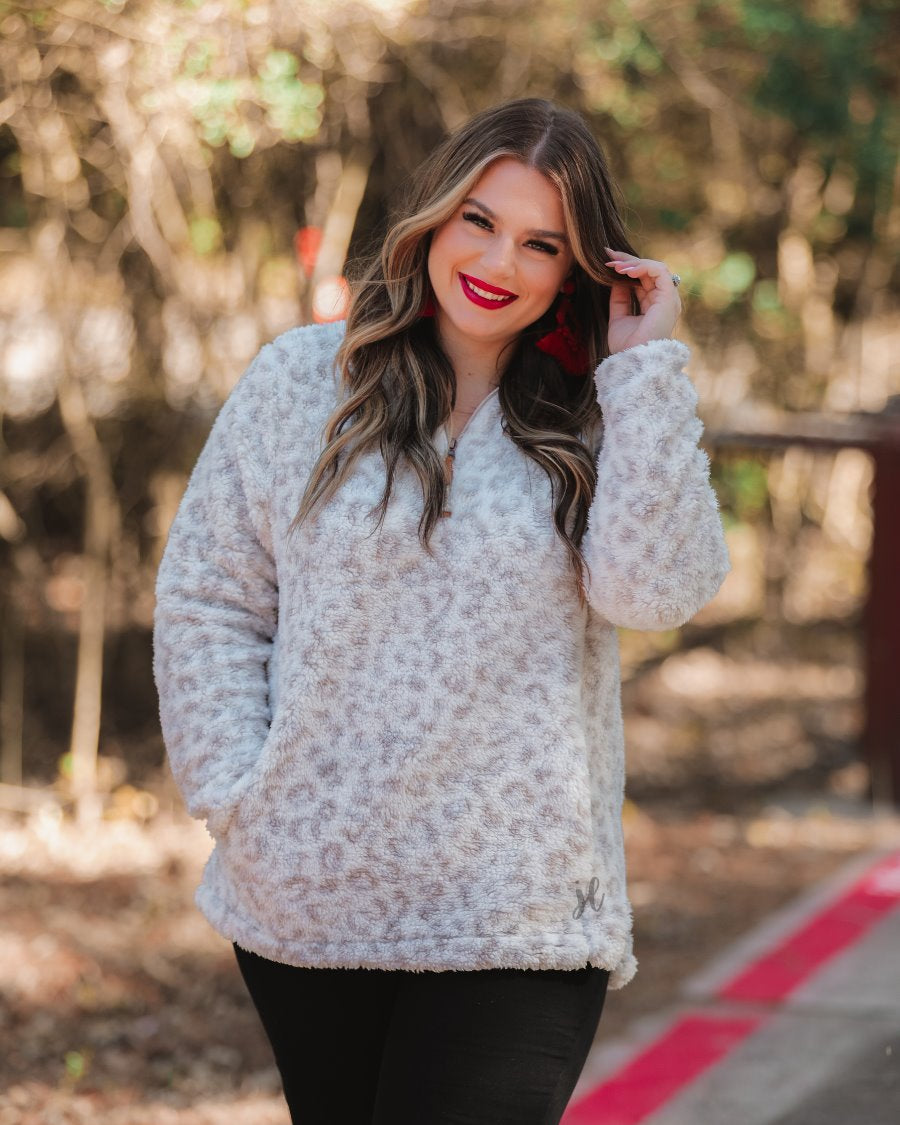 a long-sleeve fluffy pullover with a quarter zip, convenient front pockets, and a foldable collar on a neutral leopard print sherpa fabric
