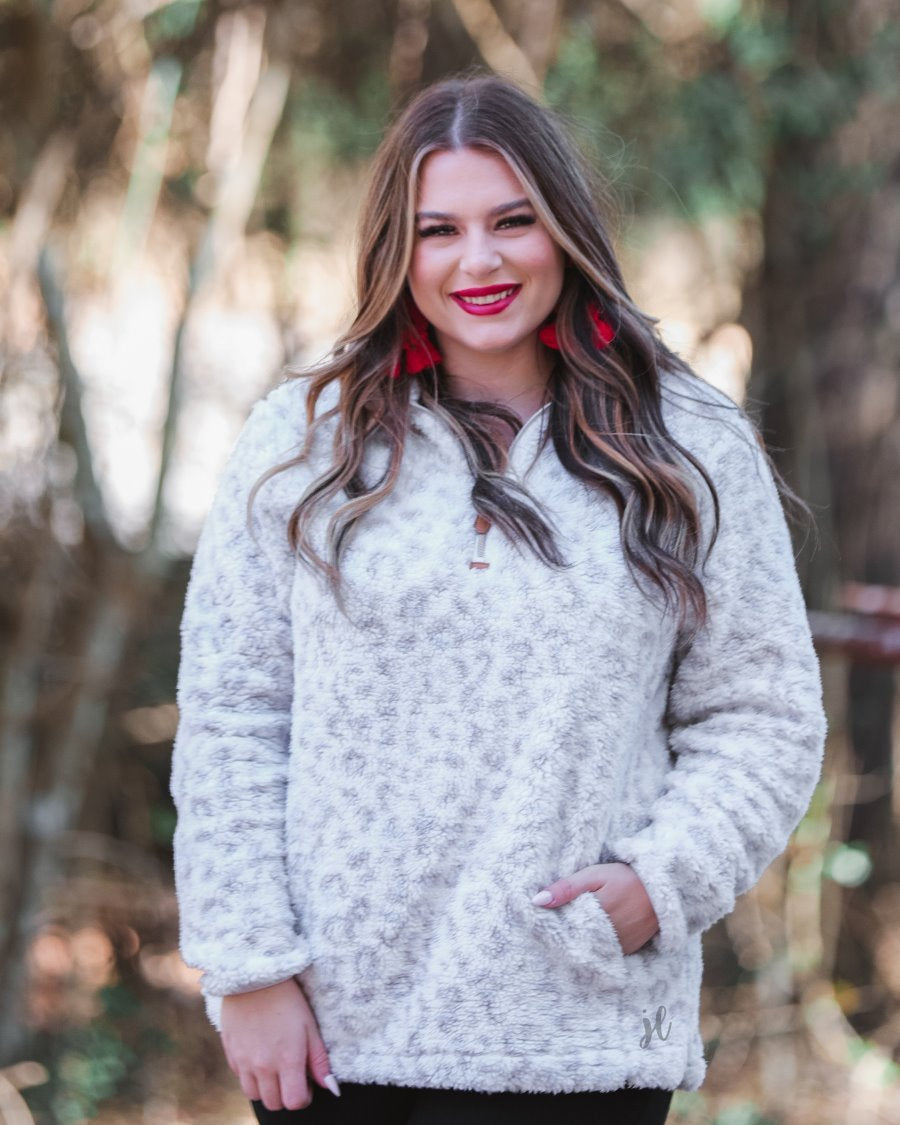a long-sleeve fluffy pullover with a quarter zip, convenient front pockets, and a foldable collar on a neutral leopard print sherpa fabric