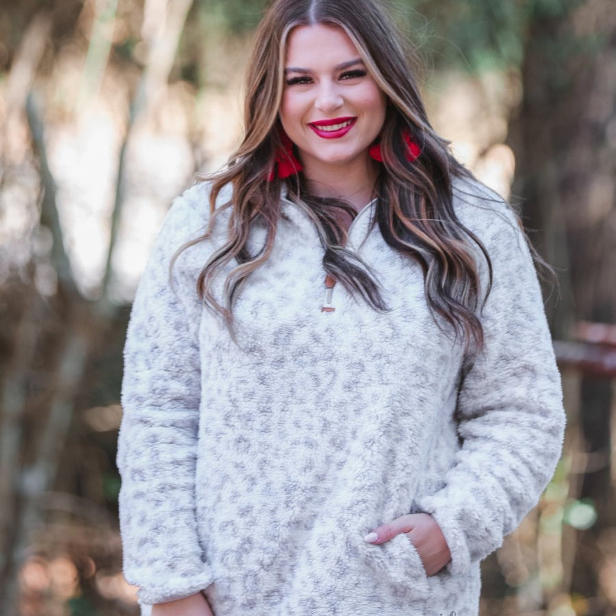 a long-sleeve fluffy pullover with a quarter zip, convenient front pockets, and a foldable collar on a neutral leopard print sherpa fabric