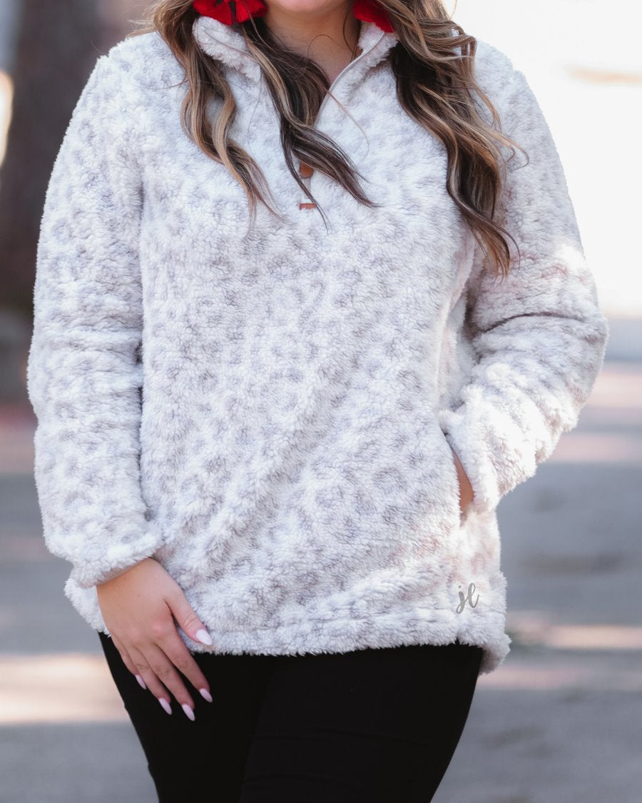 a long-sleeve fluffy pullover with a quarter zip, convenient front pockets, and a foldable collar on a neutral leopard print sherpa fabric