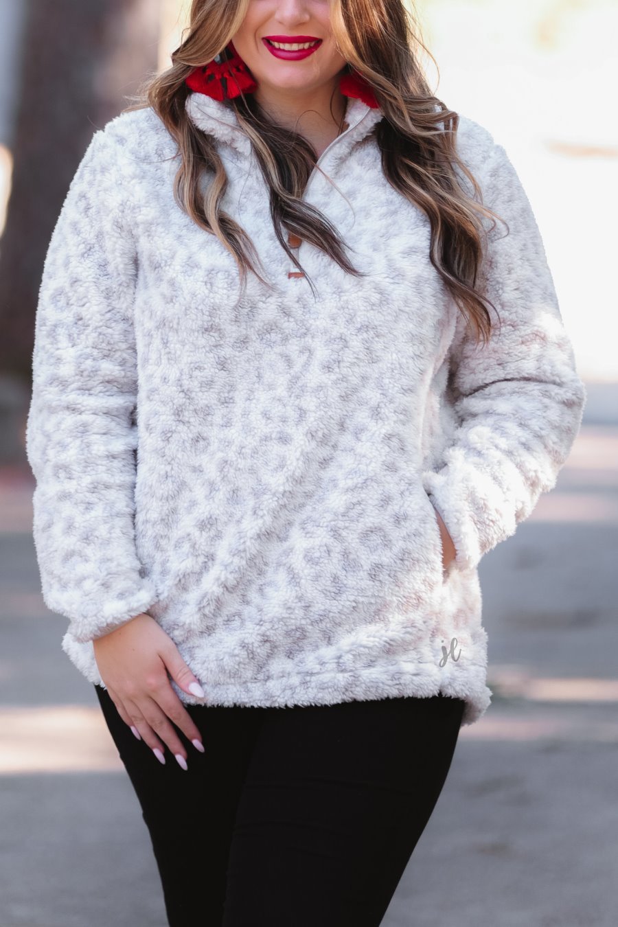 a long-sleeve fluffy pullover with a quarter zip, convenient front pockets, and a foldable collar on a neutral leopard print sherpa fabric