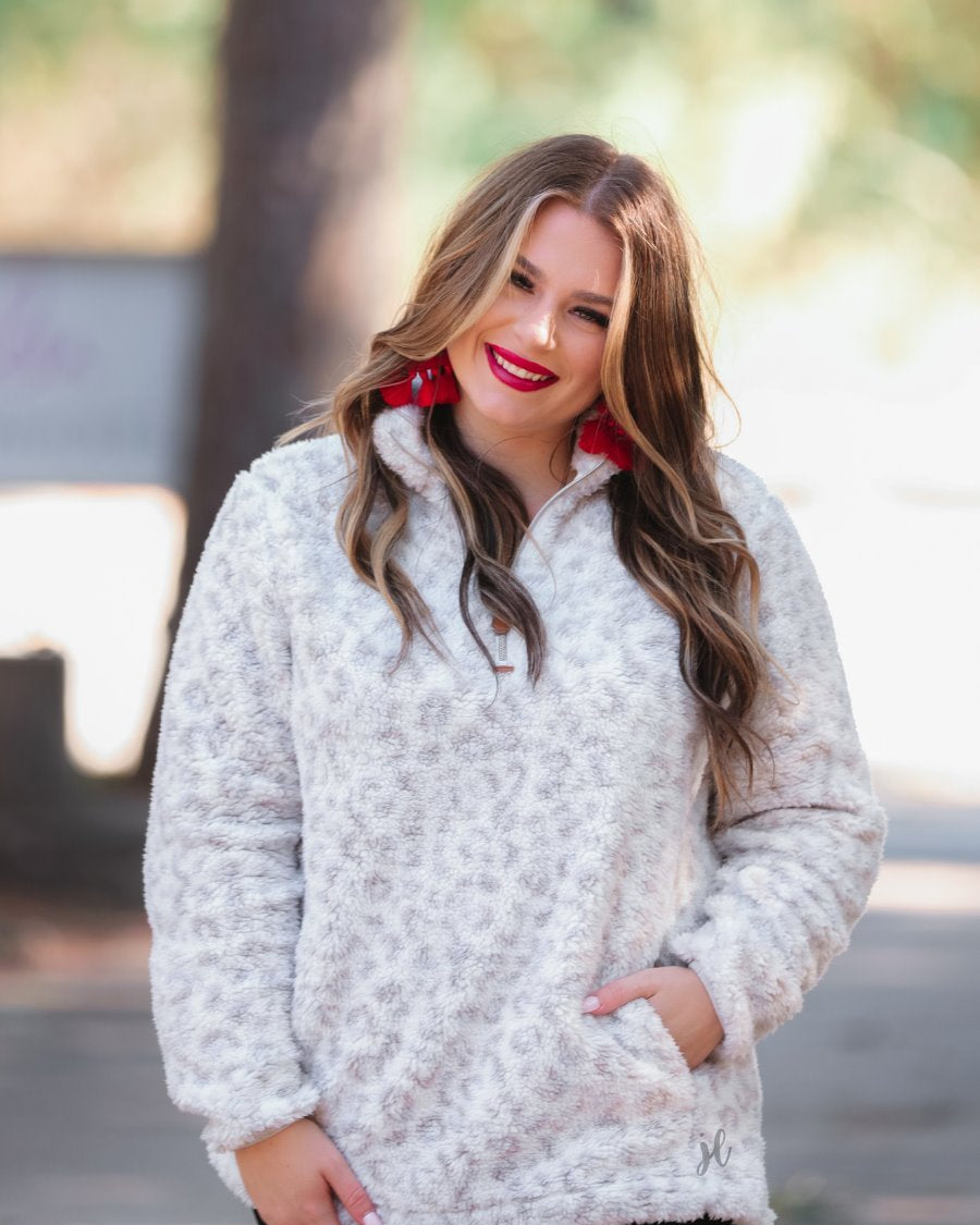 a long-sleeve fluffy pullover with a quarter zip, convenient front pockets, and a foldable collar on a neutral leopard print sherpa fabric
