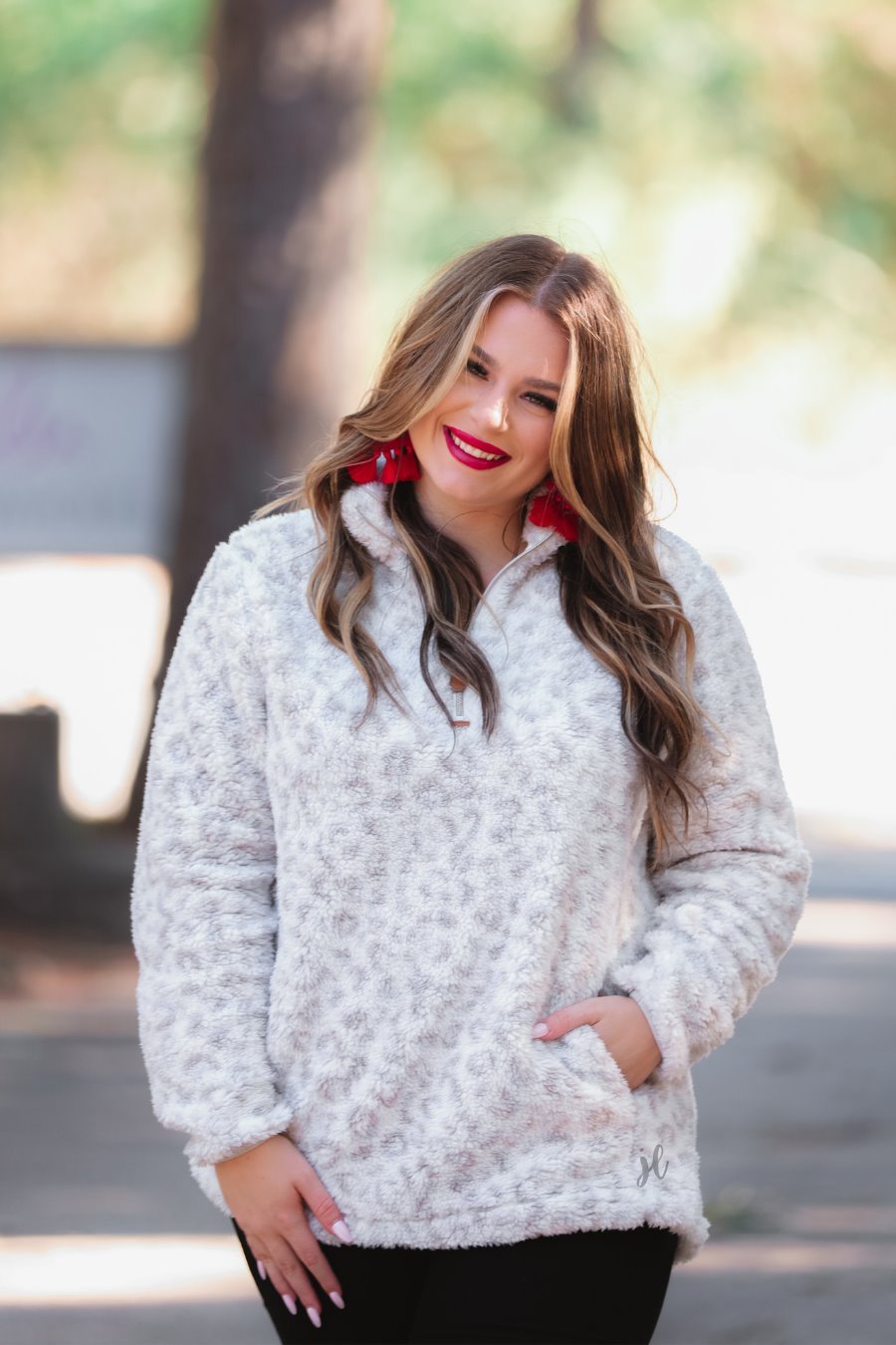 a long-sleeve fluffy pullover with a quarter zip, convenient front pockets, and a foldable collar on a neutral leopard print sherpa fabric