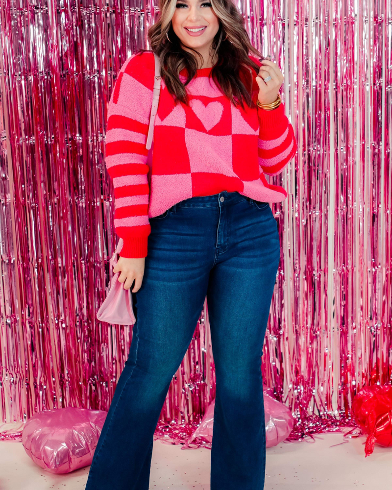 a plush fuzzy knit long-sleeve sweater with a playful mix of checkered blocks, heart motifs, and stripes on contrasting shades, a drop-shoulder fit, and ribbed detailing on the crew neckline, cuffs, and hemline