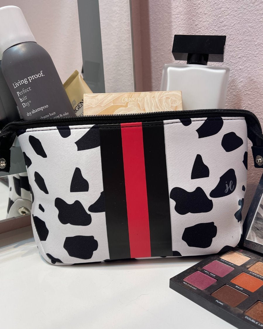 spacious cosmetic bag in a dalmation print made of neoprene, accentuated with black and red racing stripe, one top zipper, and side snap closures in silver hardware