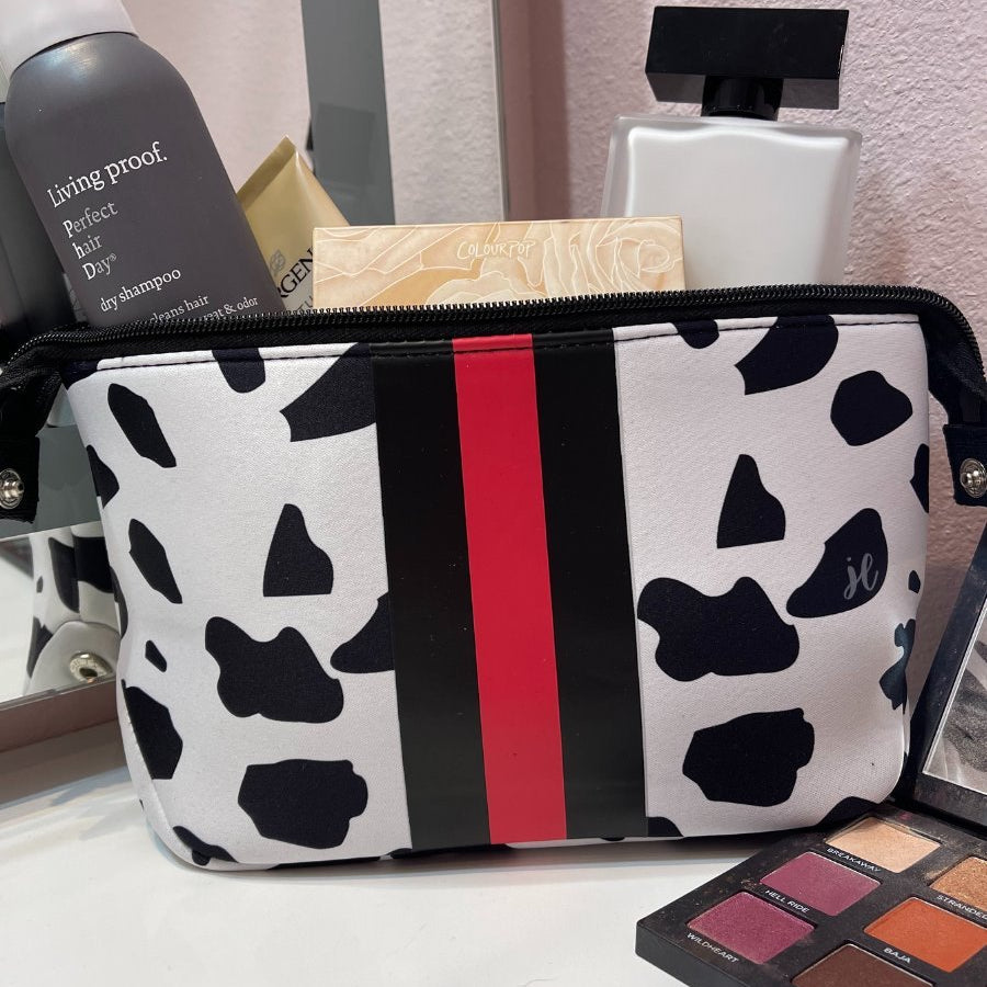 spacious cosmetic bag in a dalmation print made of neoprene, accentuated with black and red racing stripe, one top zipper, and side snap closures in silver hardware
