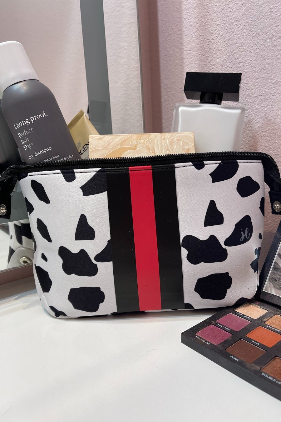spacious cosmetic bag in a dalmation print made of neoprene, accentuated with black and red racing stripe, one top zipper, and side snap closures in silver hardware