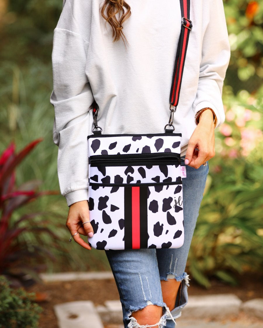 black and ivory dalmation print pattern crossbody bag made of neoprene with perfectly matched signature striped (black and red) adjustable straps and racing stripes with two front pockets (one zip, one open)
