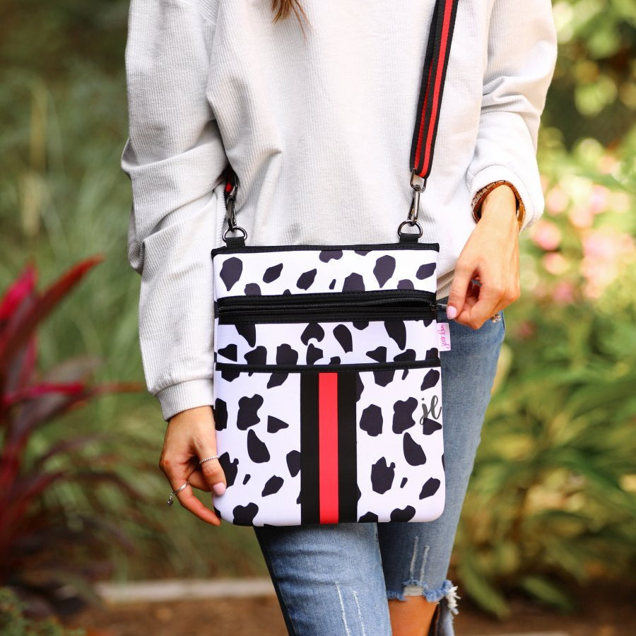 black and ivory dalmation print pattern crossbody bag made of neoprene with perfectly matched signature striped (black and red) adjustable straps and racing stripes with two front pockets (one zip, one open)