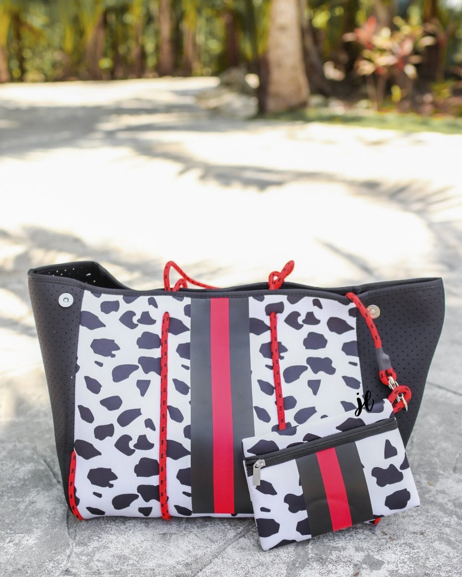 ultra-lightweight tote made of neoprene with removable hard bottom liner, paracord shoulder straps, removable matching zippered pouch, magnetic side snap closures in silver hardware, black interior (tote and pouch), and racing stripes (black and red) on black and red dalmation print pattern