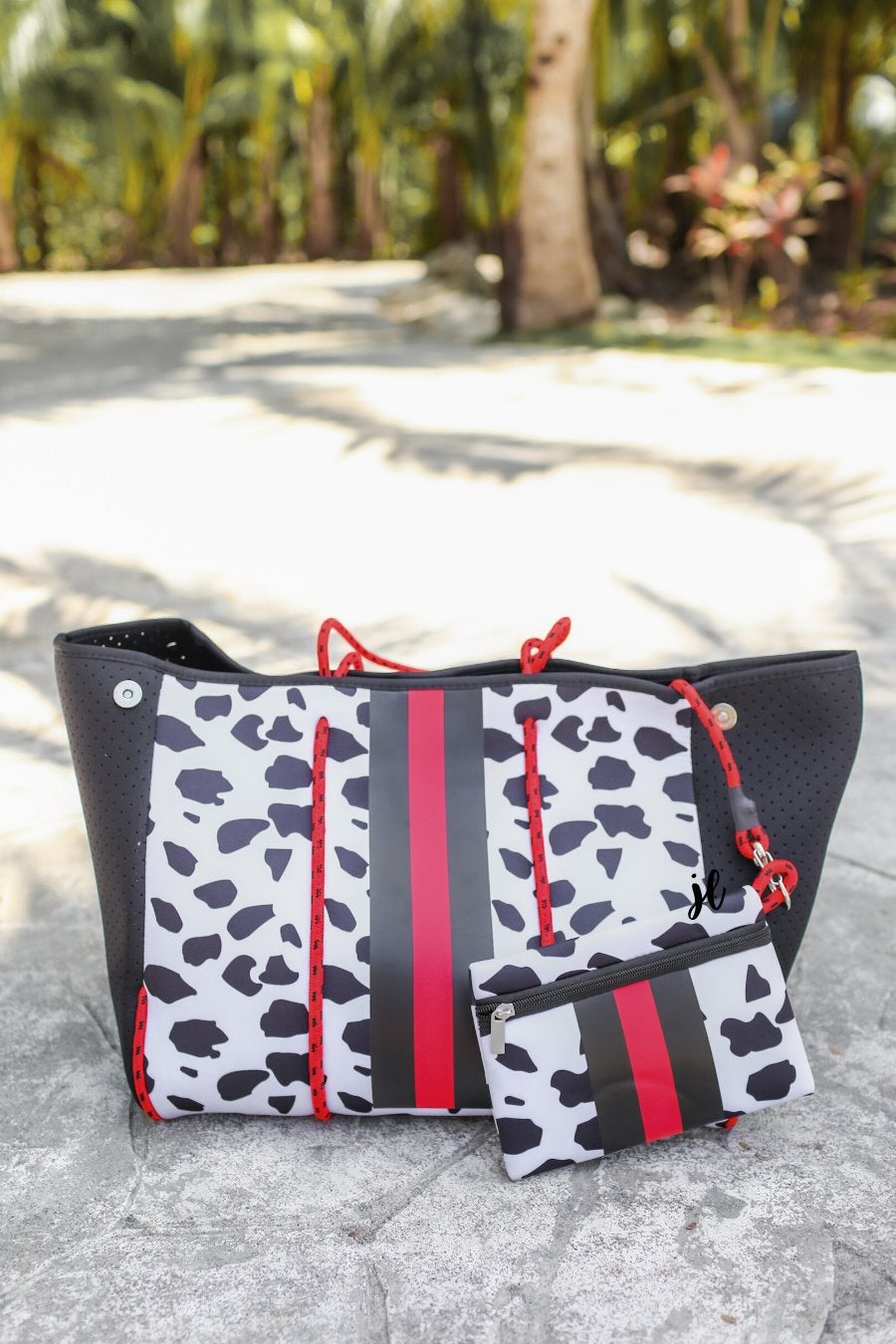 ultra-lightweight tote made of neoprene with removable hard bottom liner, paracord shoulder straps, removable matching zippered pouch, magnetic side snap closures in silver hardware, black interior (tote and pouch), and racing stripes (black and red) on black and red dalmation print pattern