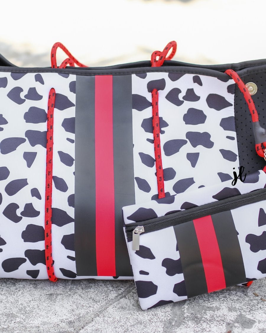 ultra-lightweight tote made of neoprene with removable hard bottom liner, paracord shoulder straps, removable matching zippered pouch, magnetic side snap closures in silver hardware, black interior (tote and pouch), and racing stripes (black and red) on black and red dalmation print pattern