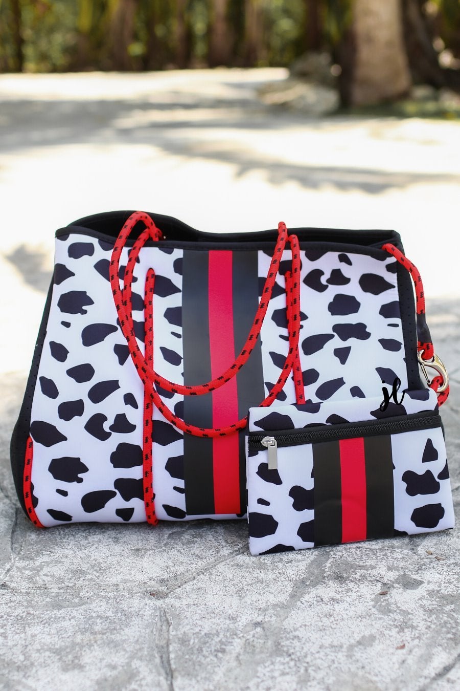ultra-lightweight tote made of neoprene with removable hard bottom liner, paracord shoulder straps, removable matching zippered pouch, magnetic side snap closures in silver hardware, black interior (tote and pouch), and racing stripes (black and red) on black and red dalmation print pattern