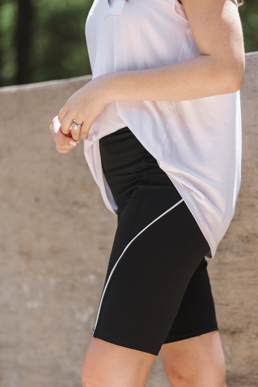 sleek black biker shorts created from lightweight stretch fabric with a white piping, high elastic waistband for tummy control, side pockets, a flattering figure-hugging short silhouette, above-knee length, and pull-on design