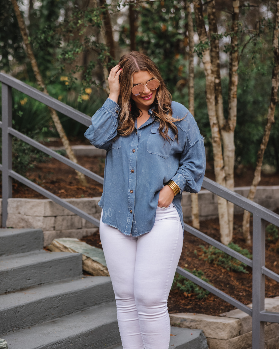 loose long-sleeve top made of soft lightweight material with a button up front, a collared neckline, button closure cuffs, two oversized accent chest pockets, and a slouched silhouette that falls into a rounded hemline with an oversized fit on an acid-washed colored fabric in chambray
