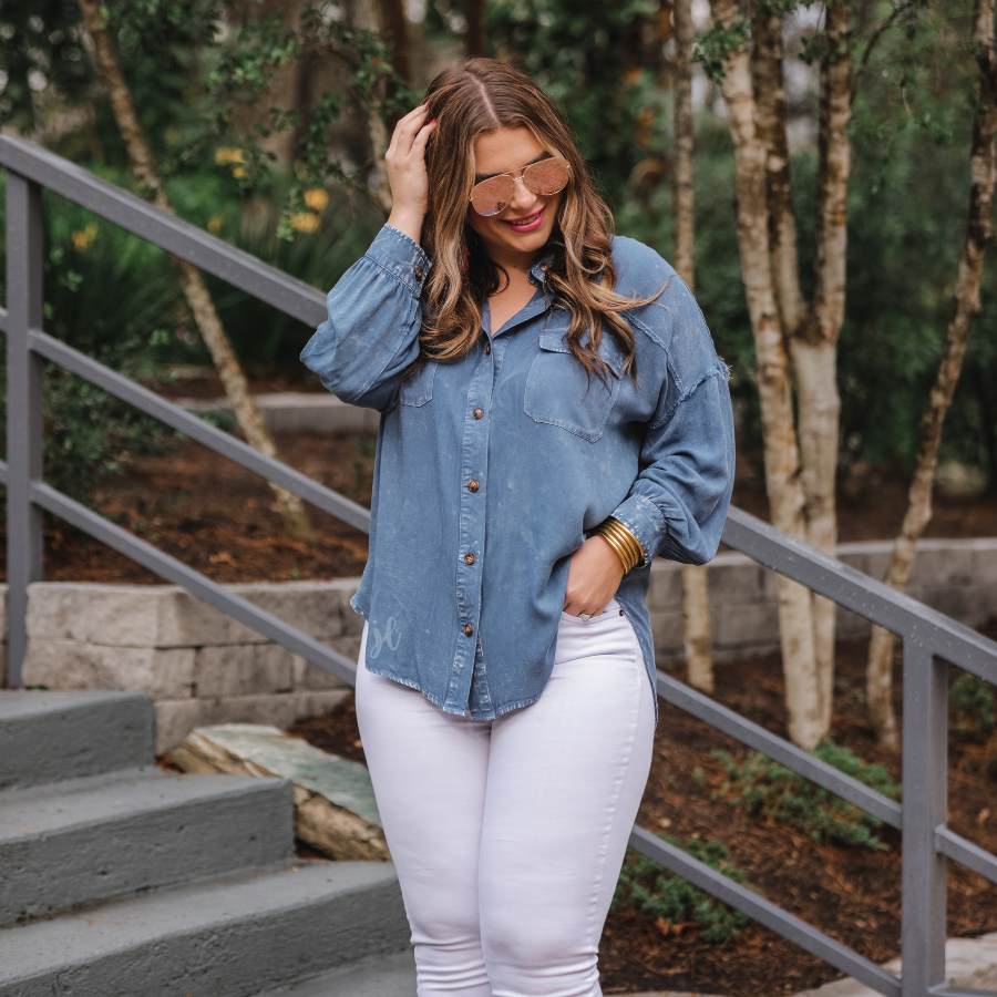 loose long-sleeve top made of soft lightweight material with a button up front, a collared neckline, button closure cuffs, two oversized accent chest pockets, and a slouched silhouette that falls into a rounded hemline with an oversized fit on an acid-washed colored fabric in chambray