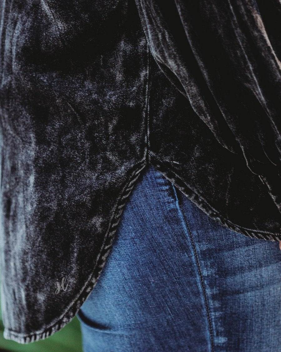 loose long-sleeve top made of soft lightweight material with a button up front, a collared neckline, button closure cuffs, two oversized accent chest pockets, and a slouched silhouette that falls into a rounded hemline with an oversized fit on an acid-washed colored fabric in black