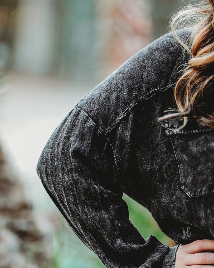 loose long-sleeve top made of soft lightweight material with a button up front, a collared neckline, button closure cuffs, two oversized accent chest pockets, and a slouched silhouette that falls into a rounded hemline with an oversized fit on an acid-washed colored fabric in black