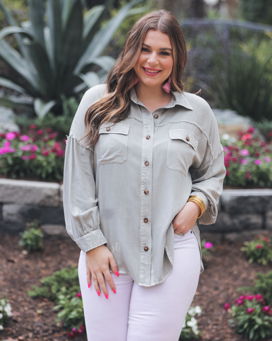 loose long-sleeve top made of soft lightweight material with a button up front, a collared neckline, button closure cuffs, two oversized accent chest pockets, and a slouched silhouette that falls into a rounded hemline with an oversized fit on an acid-washed colored fabric in grey