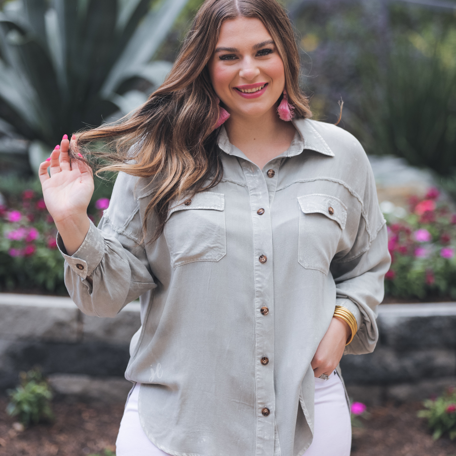loose long-sleeve top made of soft lightweight material with a button up front, a collared neckline, button closure cuffs, two oversized accent chest pockets, and a slouched silhouette that falls into a rounded hemline with an oversized fit on an acid-washed colored fabric in grey