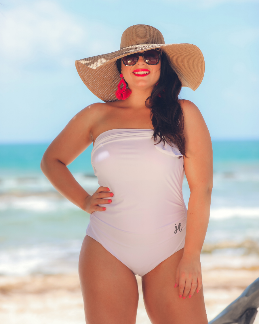 white one-piece swimsuit made of lightweight stretchy material with a one-shoulder neckline, a white matching bow, an adjustable strap, and a padded bust