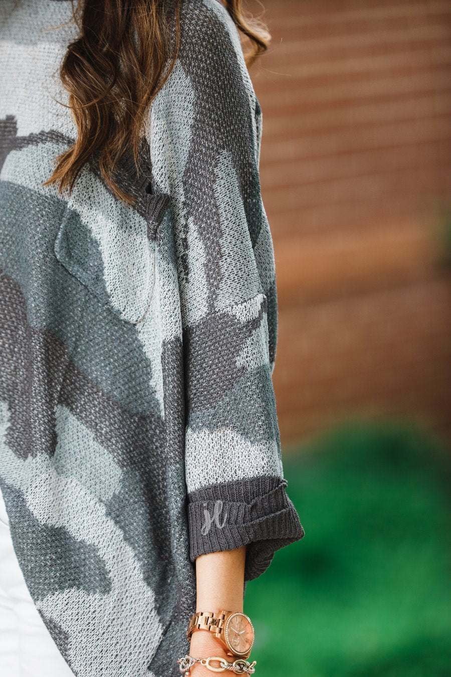 three-quarter cuffed sleeve unlined sweater crafted from a loose knit material with an oversized fit, a rounded neckline, a chest pocket, and trim on the collar, hem, and pocket on a grey camouflage pattern and charcoal base