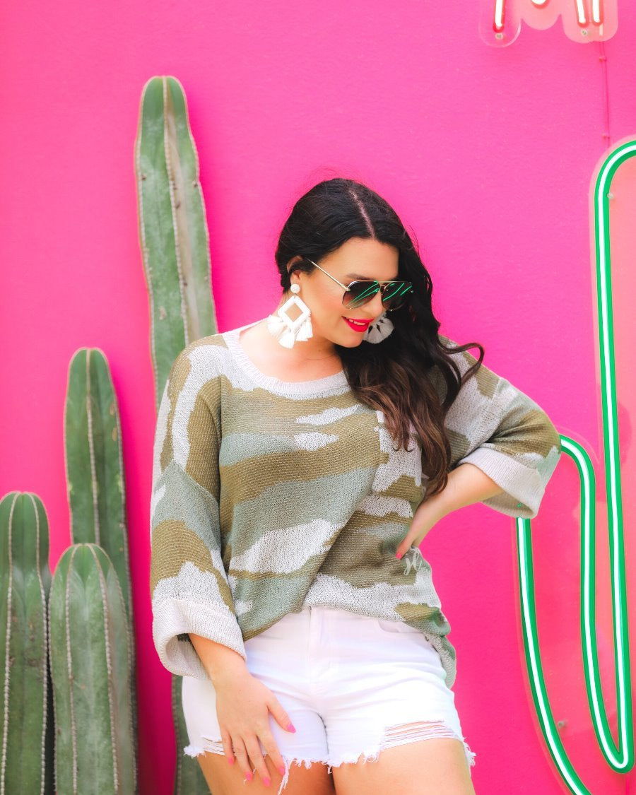 three-quarter cuffed sleeve unlined sweater crafted from a loose knit material with an oversized fit, a rounded neckline, a chest pocket, and trim on the collar, hem, and pocket on a green camouflage pattern and grey base