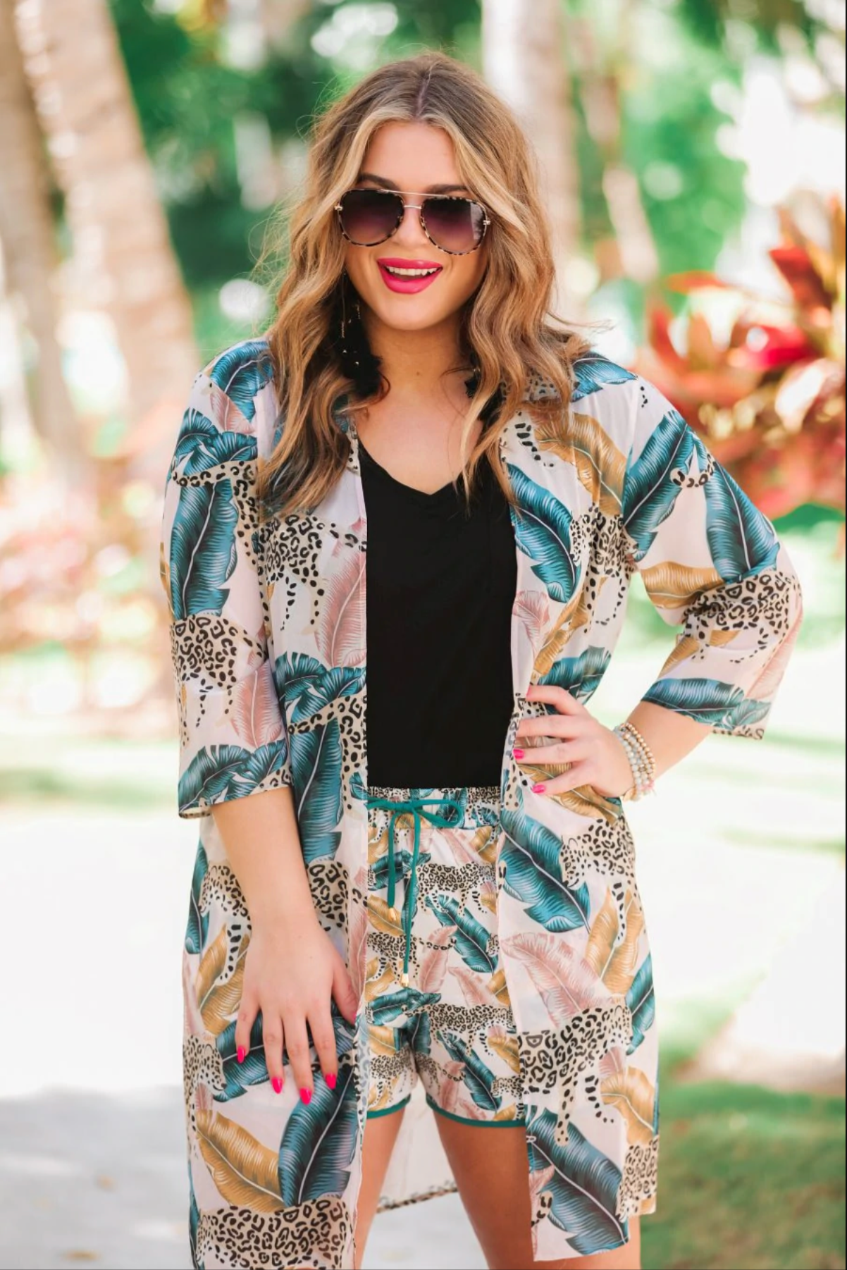 mid-rise relaxed fit activewear shorts with side pockets and a tie waist drawstring with gold bead accents, designed on a feather and tiger pattern print fabric, blush base, and teal trim