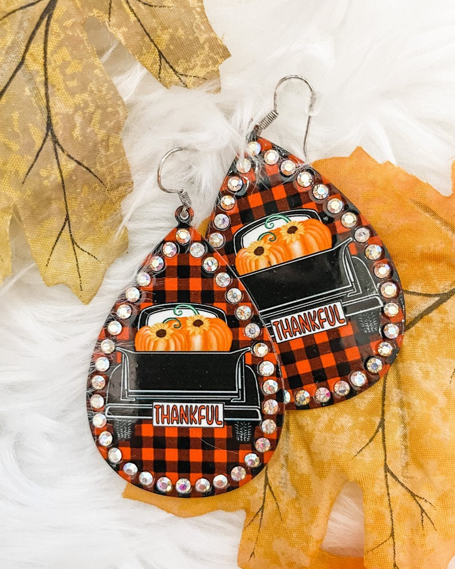 lightweight, seasonal-inspired leopard-theme teardrop-shaped earrings outlined in rhinestones with a fish hook in buffalo plaid pumpkin truck