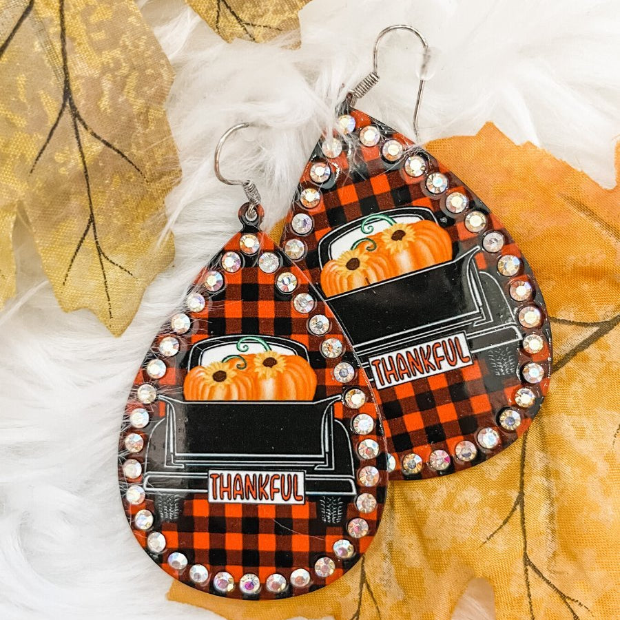lightweight, seasonal-inspired leopard-theme teardrop-shaped earrings outlined in rhinestones with a fish hook in buffalo plaid pumpkin truck