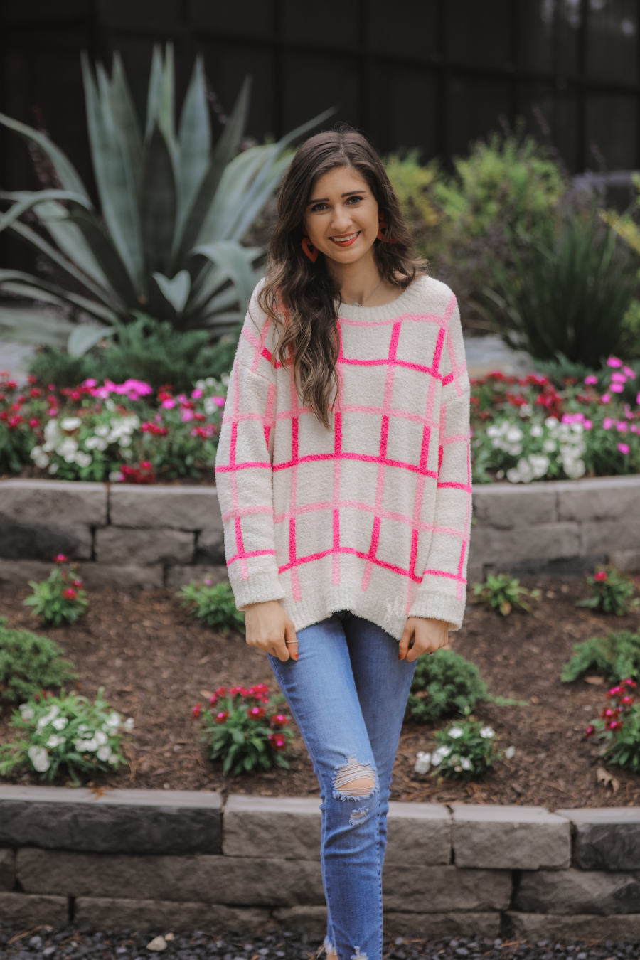 a plush knit long-sleeve sweater with a pink and ivory plaid pattern, relaxed drop-shoulder fit, classic round neckline, and ribbed detailing at the cuffs, sleeves, and hemline for a clean, polished finish