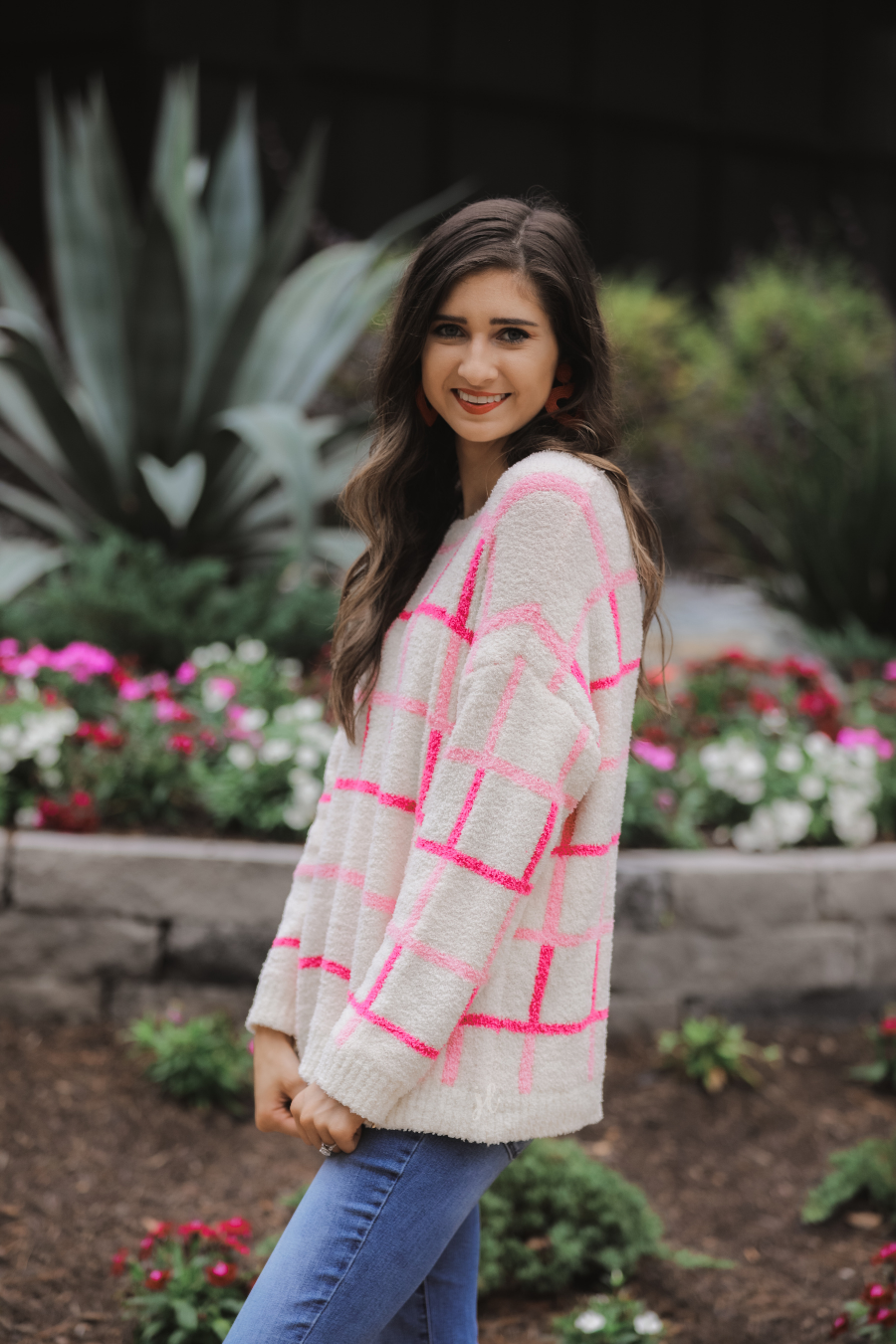 a plush knit long-sleeve sweater with a pink and ivory plaid pattern, relaxed drop-shoulder fit, classic round neckline, and ribbed detailing at the cuffs, sleeves, and hemline for a clean, polished finish