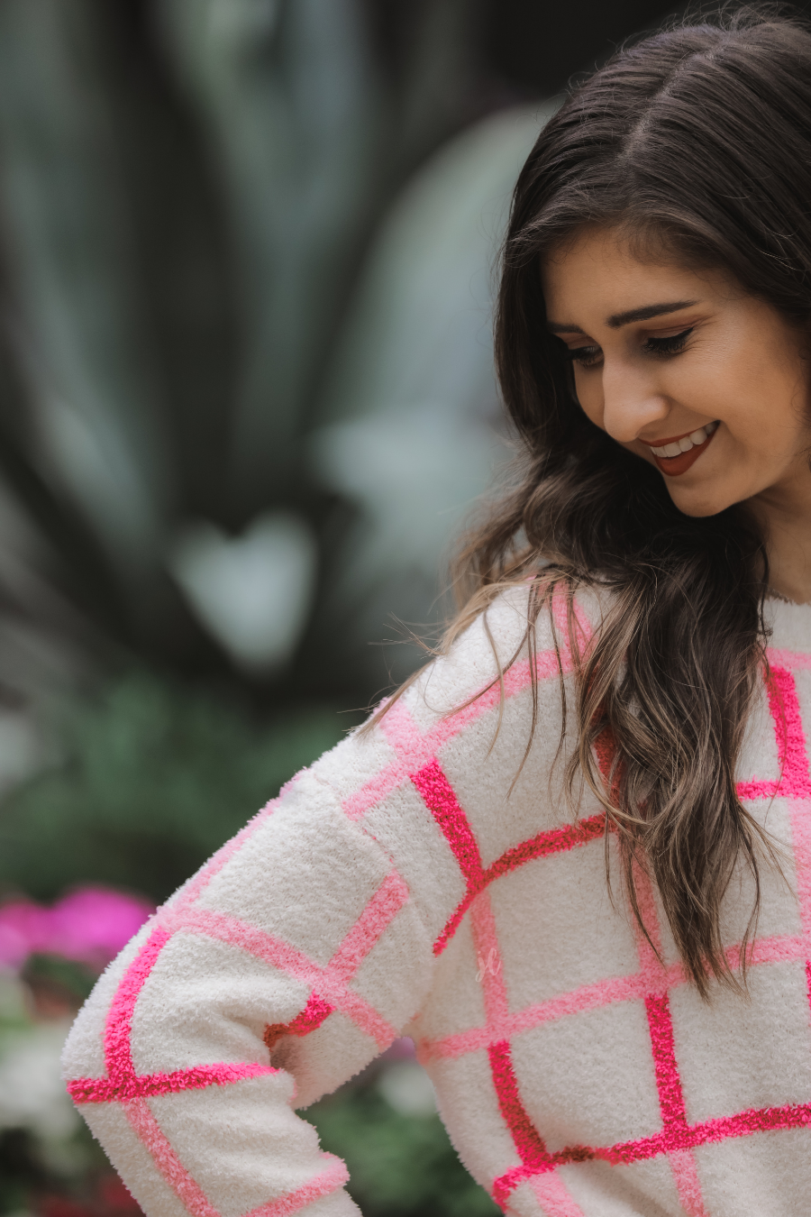 a plush knit long-sleeve sweater with a pink and ivory plaid pattern, relaxed drop-shoulder fit, classic round neckline, and ribbed detailing at the cuffs, sleeves, and hemline for a clean, polished finish