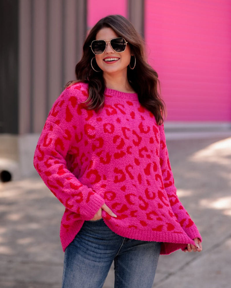 a fuzzy textured long-sleeve sweater with a vibrant pink leopard pattern on a pink base and ribbed detailing on the round neckline, cuffs, and structured hemline