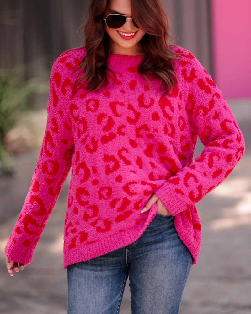 a fuzzy textured long-sleeve sweater with a vibrant pink leopard pattern on a pink base and ribbed detailing on the round neckline, cuffs, and structured hemline