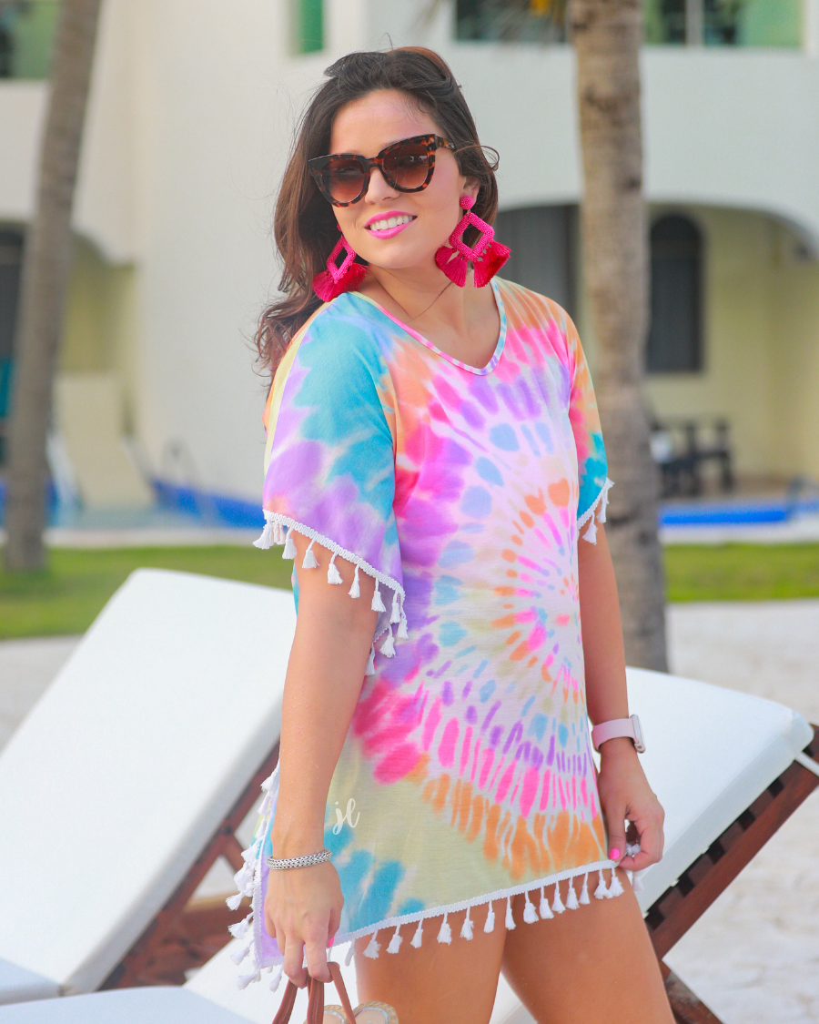 short sleeve lightweight coverup made of breathable fabric with a vibrant tie-dye print pattern, a high v-neckline, open sides with an arm opening, and side tassels