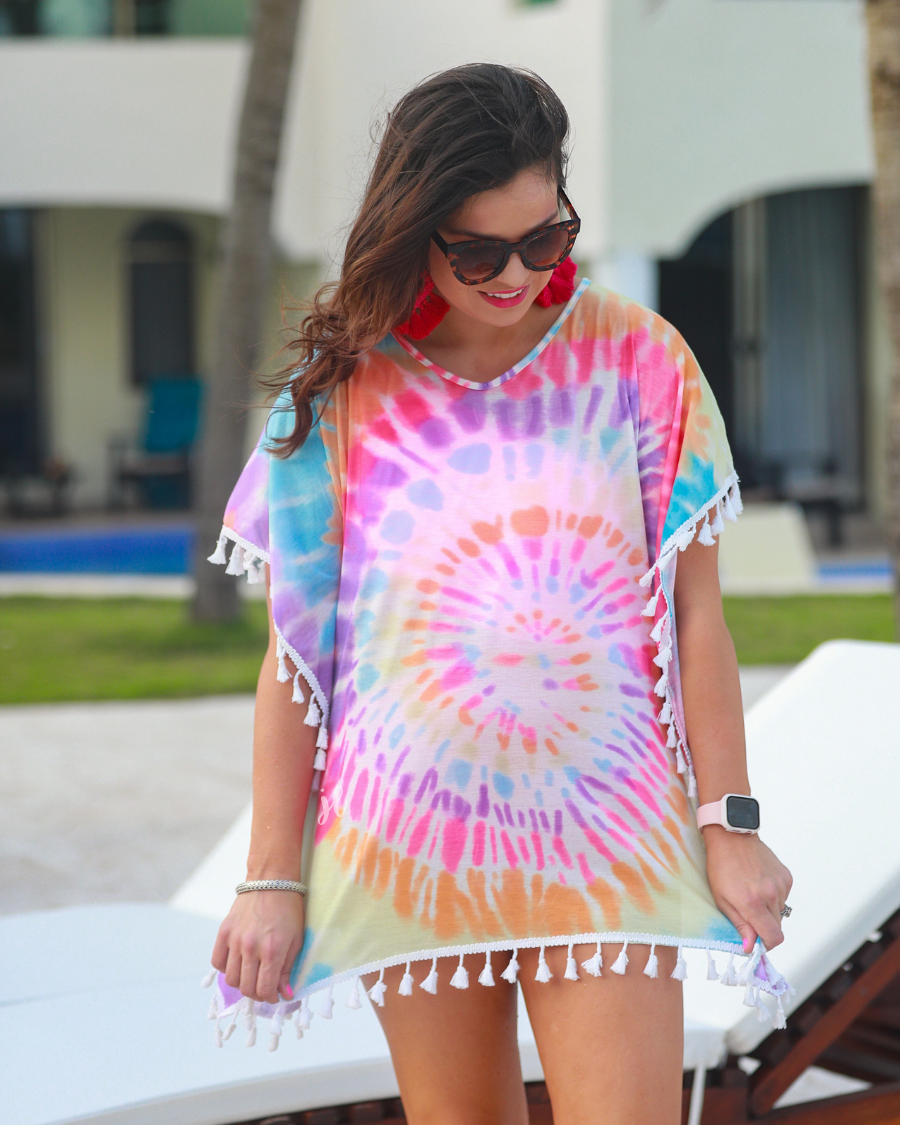 short sleeve lightweight coverup made of breathable fabric with a vibrant tie-dye print pattern, a high v-neckline, open sides with an arm opening, and side tassels