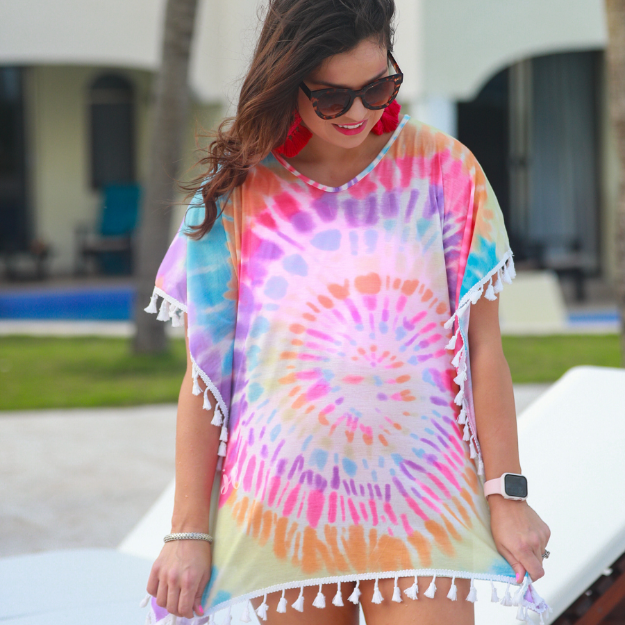 short sleeve lightweight coverup made of breathable fabric with a vibrant tie-dye print pattern, a high v-neckline, open sides with an arm opening, and side tassels