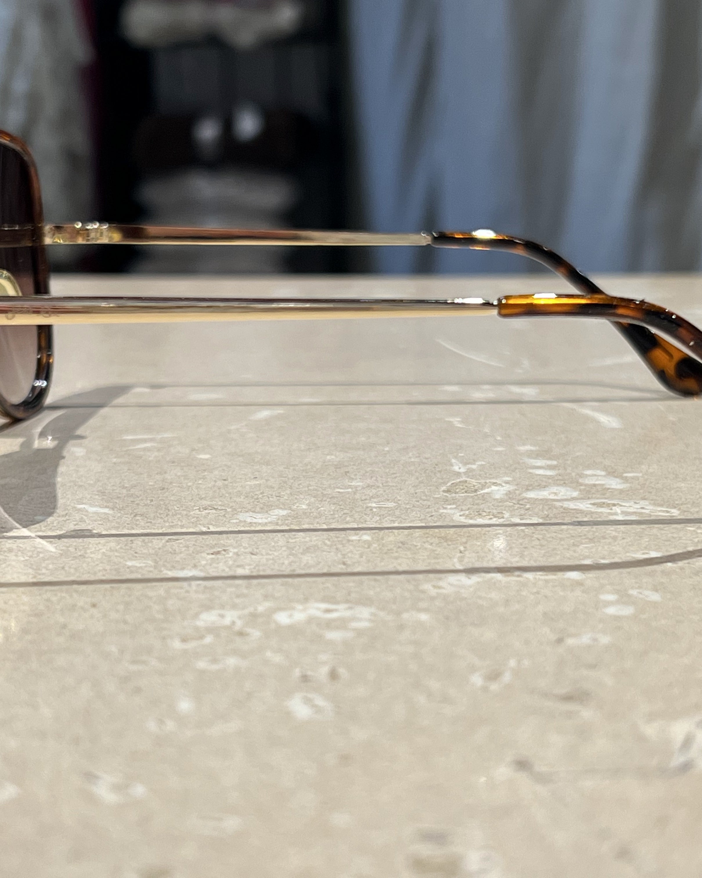brown aviator sunglasses with thin round wireframes, tinted lenses, UV protection, and brand name detail (on both the temple and the complimentary black pouch)