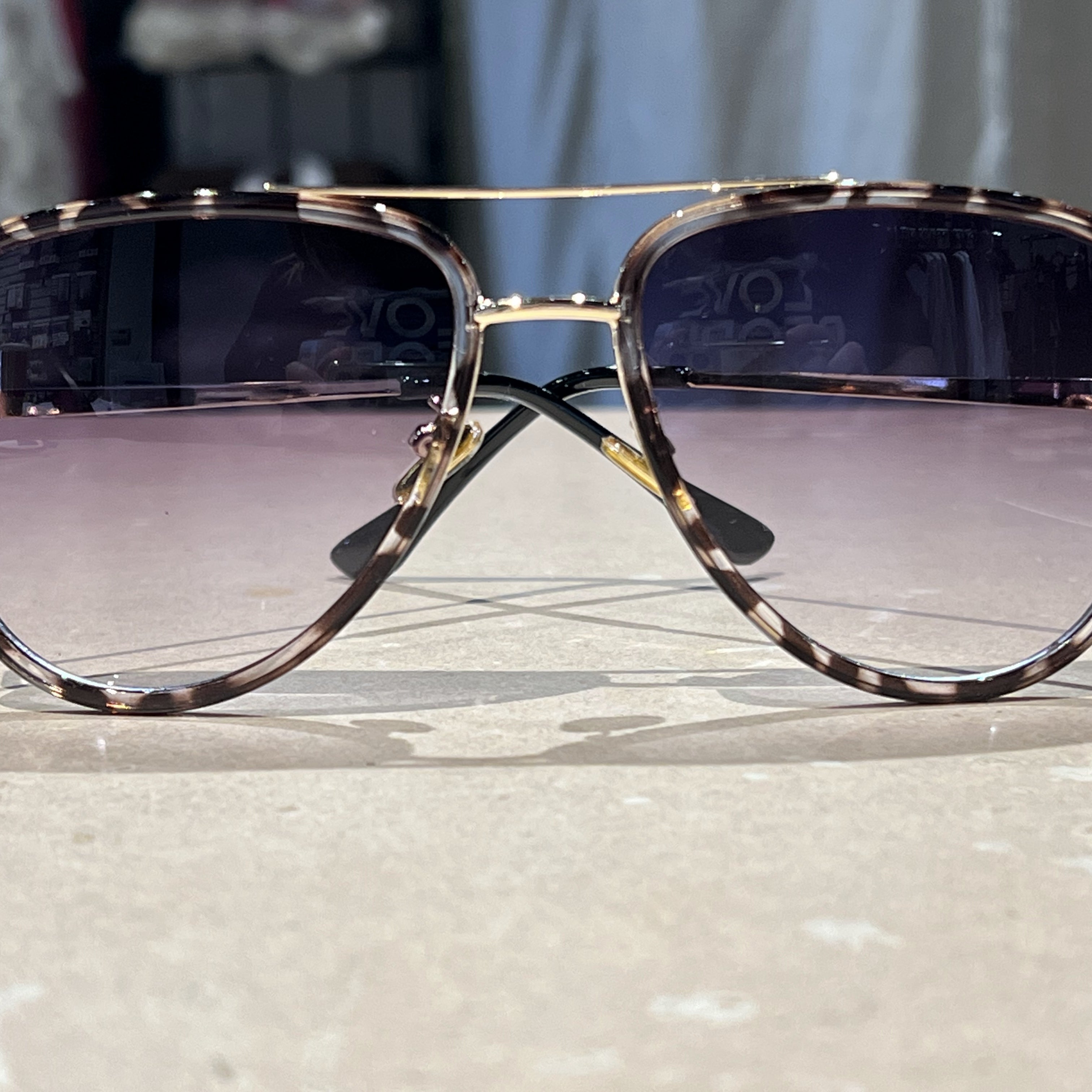 grey aviator sunglasses with thin round wireframes, tinted lenses, UV protection, and brand name detail (on both the temple and the complimentary black pouch)