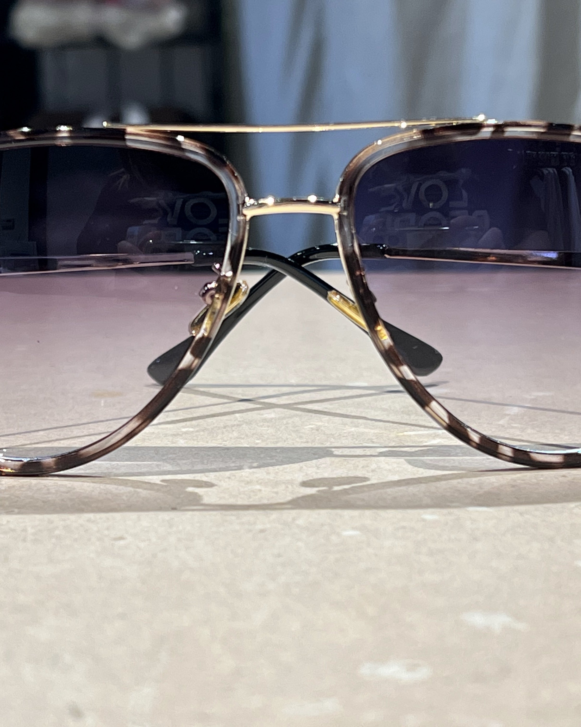 grey aviator sunglasses with thin round wireframes, tinted lenses, UV protection, and brand name detail (on both the temple and the complimentary black pouch)