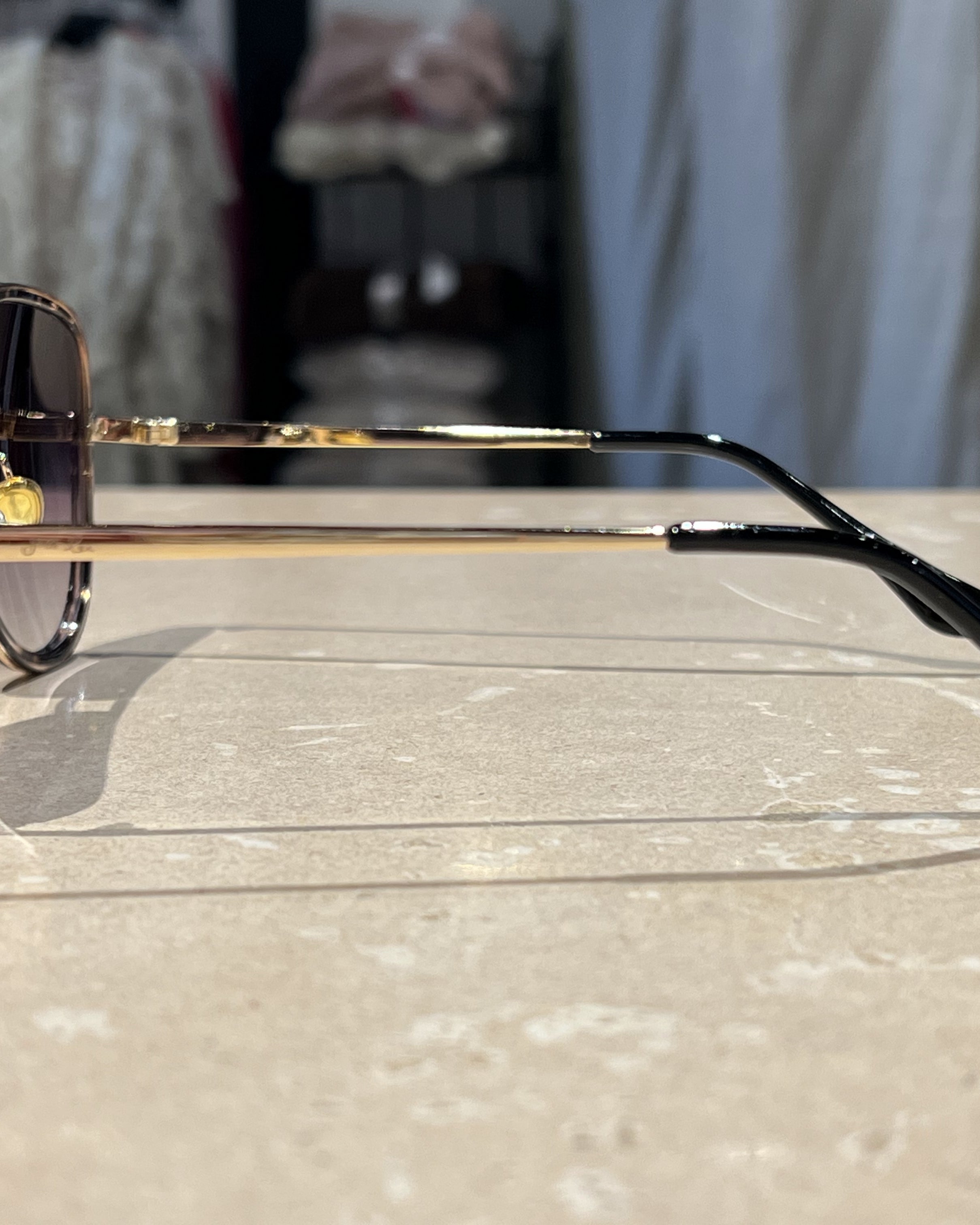 grey aviator sunglasses with thin round wireframes, tinted lenses, UV protection, and brand name detail (on both the temple and the complimentary black pouch)