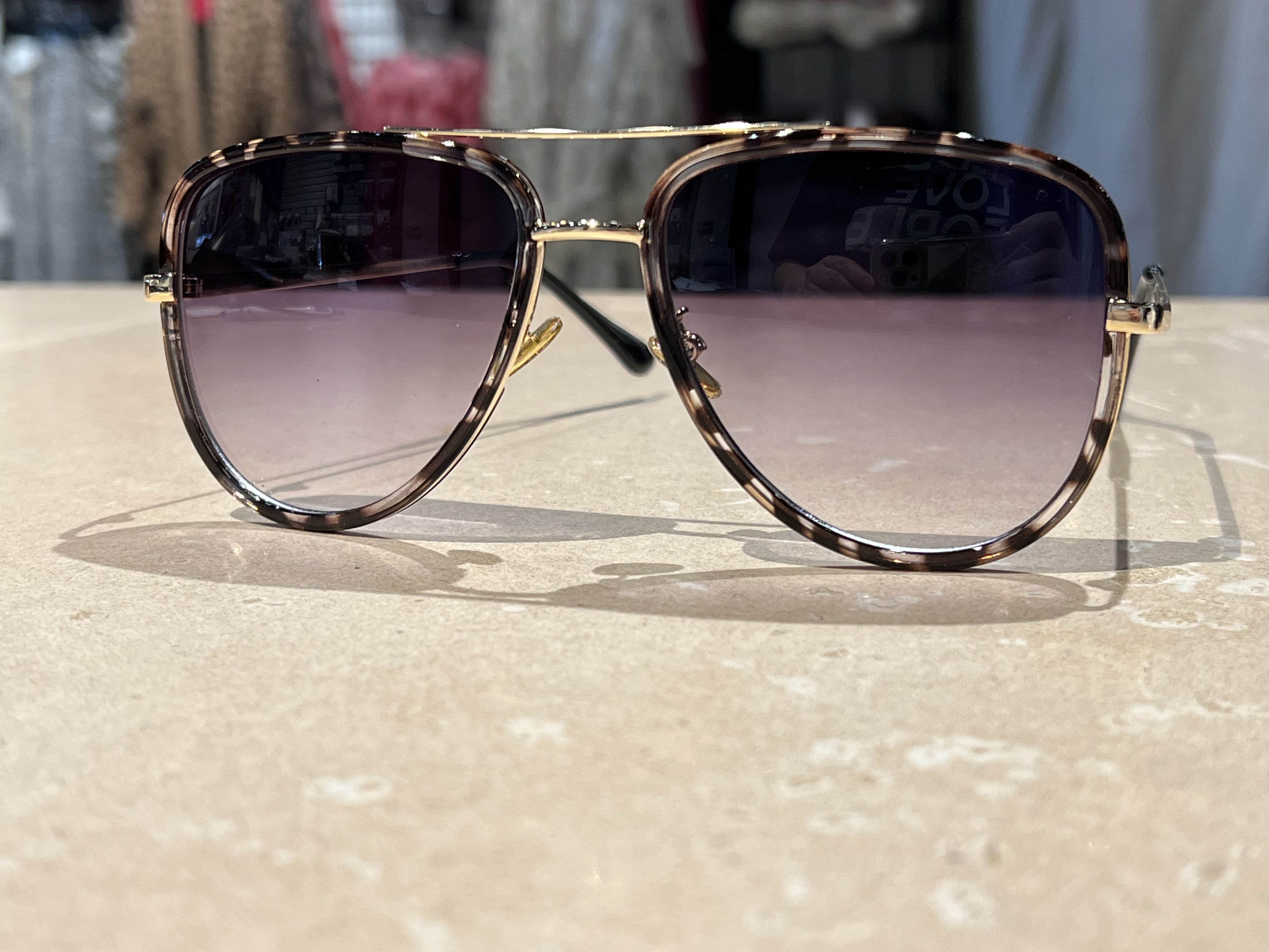 grey aviator sunglasses with thin round wireframes, tinted lenses, UV protection, and brand name detail (on both the temple and the complimentary black pouch)