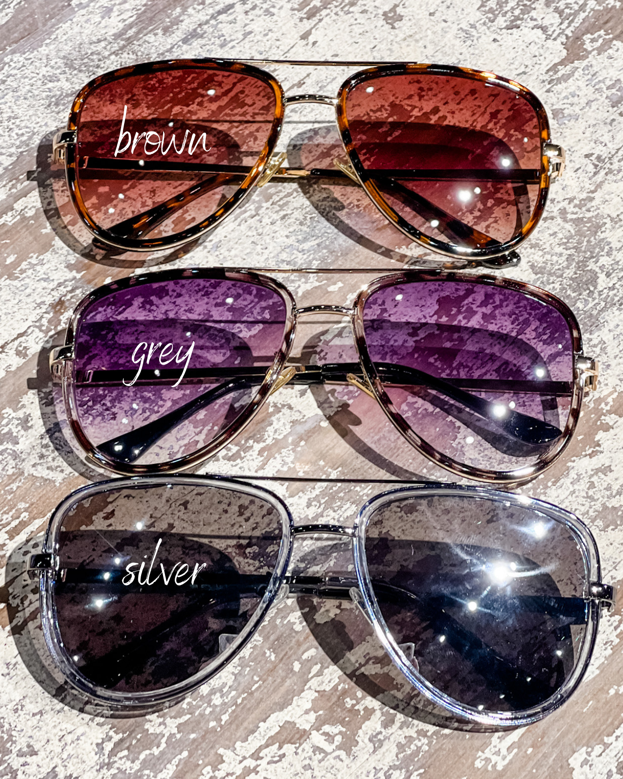 brown, grey, and silver aviator sunglasses with thin round wireframes, tinted lenses, UV protection, and brand name detail (on both the temple and the complimentary black pouch)