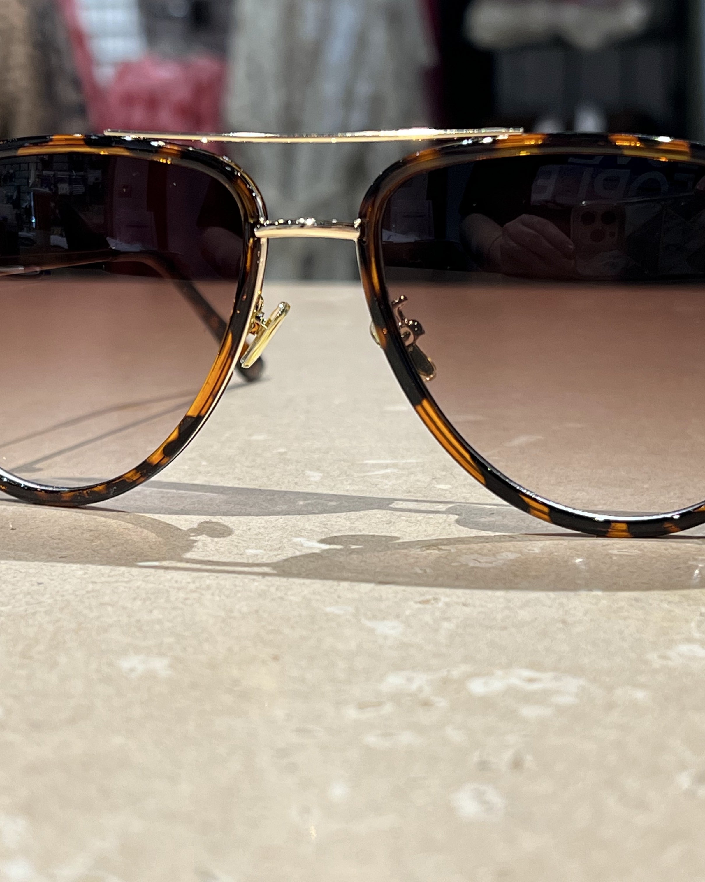 brown aviator sunglasses with thin round wireframes, tinted lenses, UV protection, and brand name detail (on both the temple and the complimentary black pouch)