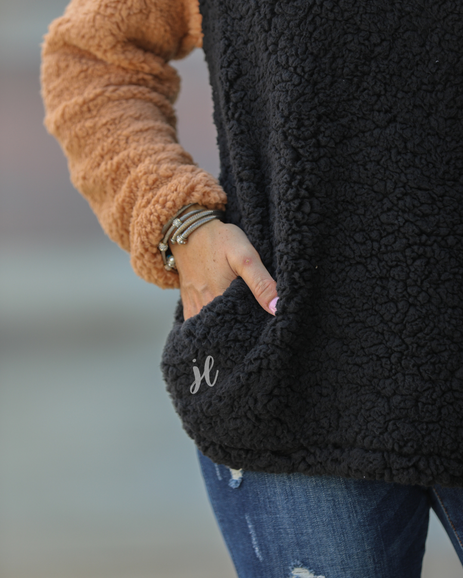 a long-sleeve fluffy pullover with a quarter-leopard snap closure, a faux leopard front chest pocket, a foldable collar, and convenient side pockets on a black, taupe, and white color block fabric that is slightly oversized