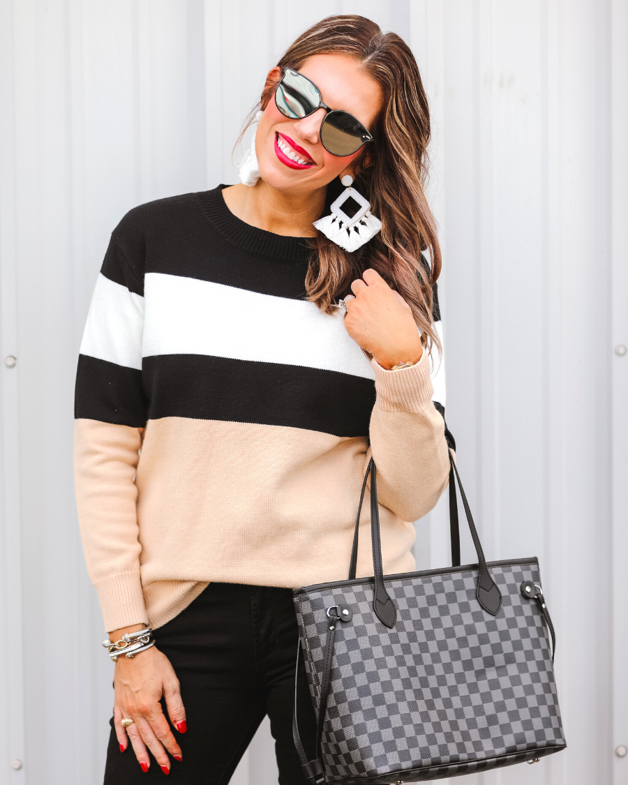 long-sleeve sweater crafted from a soft mid weight knit with bold horizontal blocks of black, tan, and white