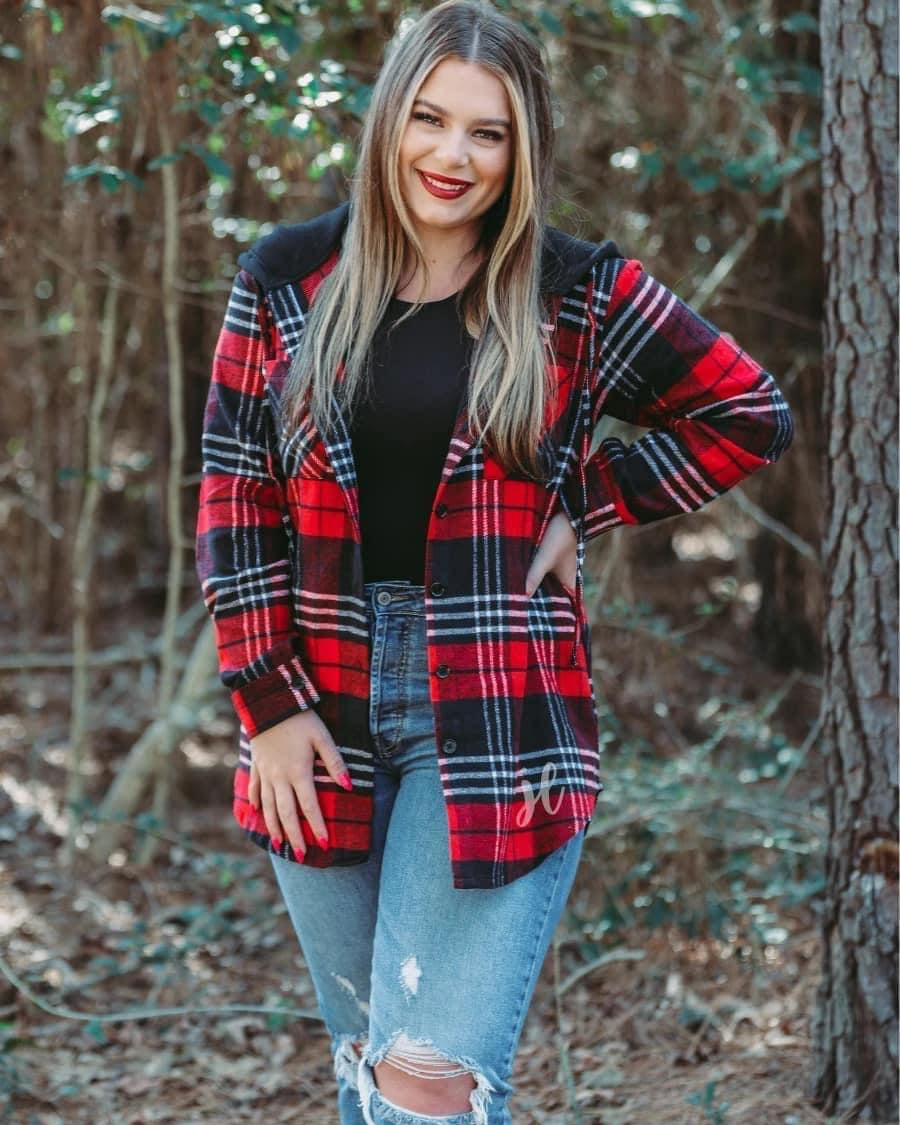 loose long sleeve shacket with fitted button closure cuffs, a button-down front, two chest pockets, a high-low hem, and a pull-string hood on a shirt material with a red plaid print