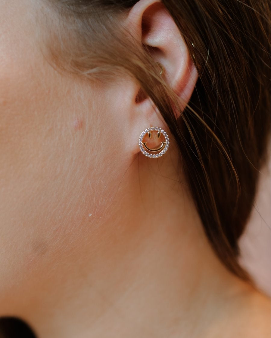stud earrings in the shape of a gold happy face surrounded by sparkling rhinestones